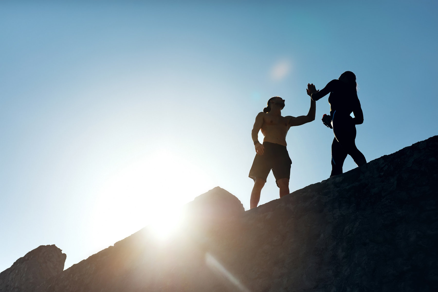Two people high-fiving on a mountain at sunrise